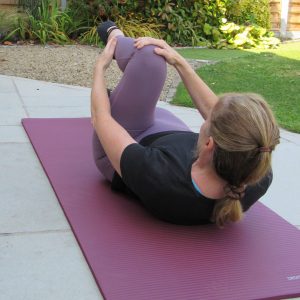 Woman performing Pilates movement outdoors